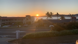 Ein Gebäude mit Parkplatz und Blick auf den Sonnenuntergang über dem Wasser.