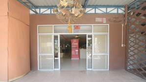Entrada de hotel con puerta de cristal, un letrero que ofrece descargas gratuitas y un árbol decorativo.