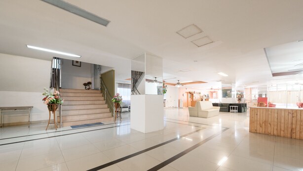Un vestíbulo amplio con una escalera, un mostrador de recepción y una zona de estar.