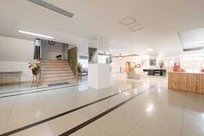 Un vestíbulo amplio con una escalera, un mostrador de recepción y una zona de estar.