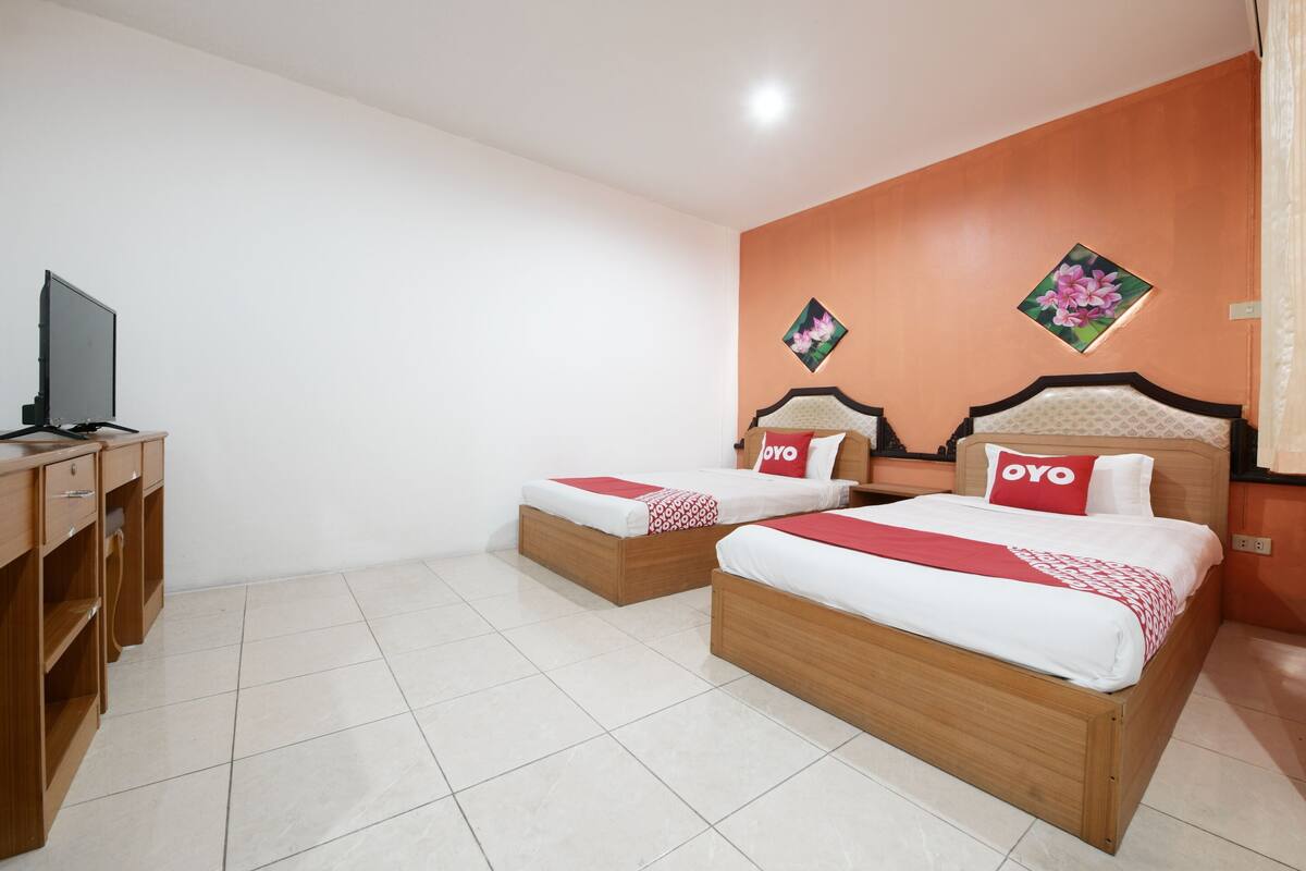 A hotel room with two beds, a TV, and a desk.