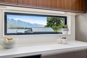 Enjoy a mountain view from the kitchen window, where a potted plant and fresh fruit add a touch of warmth.