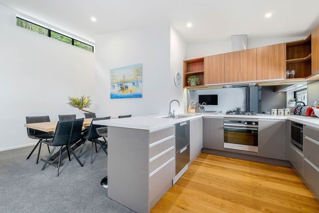 Une cuisine moderne dotée d’un îlot central, de meubles en bois et d’un coin repas avec une table et des chaises.