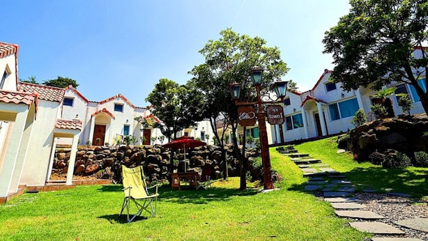 A residential area with white houses, a stone pathway, and a chair. - Eltz Town Pension (Jeju City)