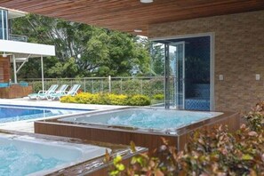 A spa area with a hot tub and a pool, surrounded by lounge chairs and greenery. -  Libertg Hotels Spa Medellin (Copacabana)