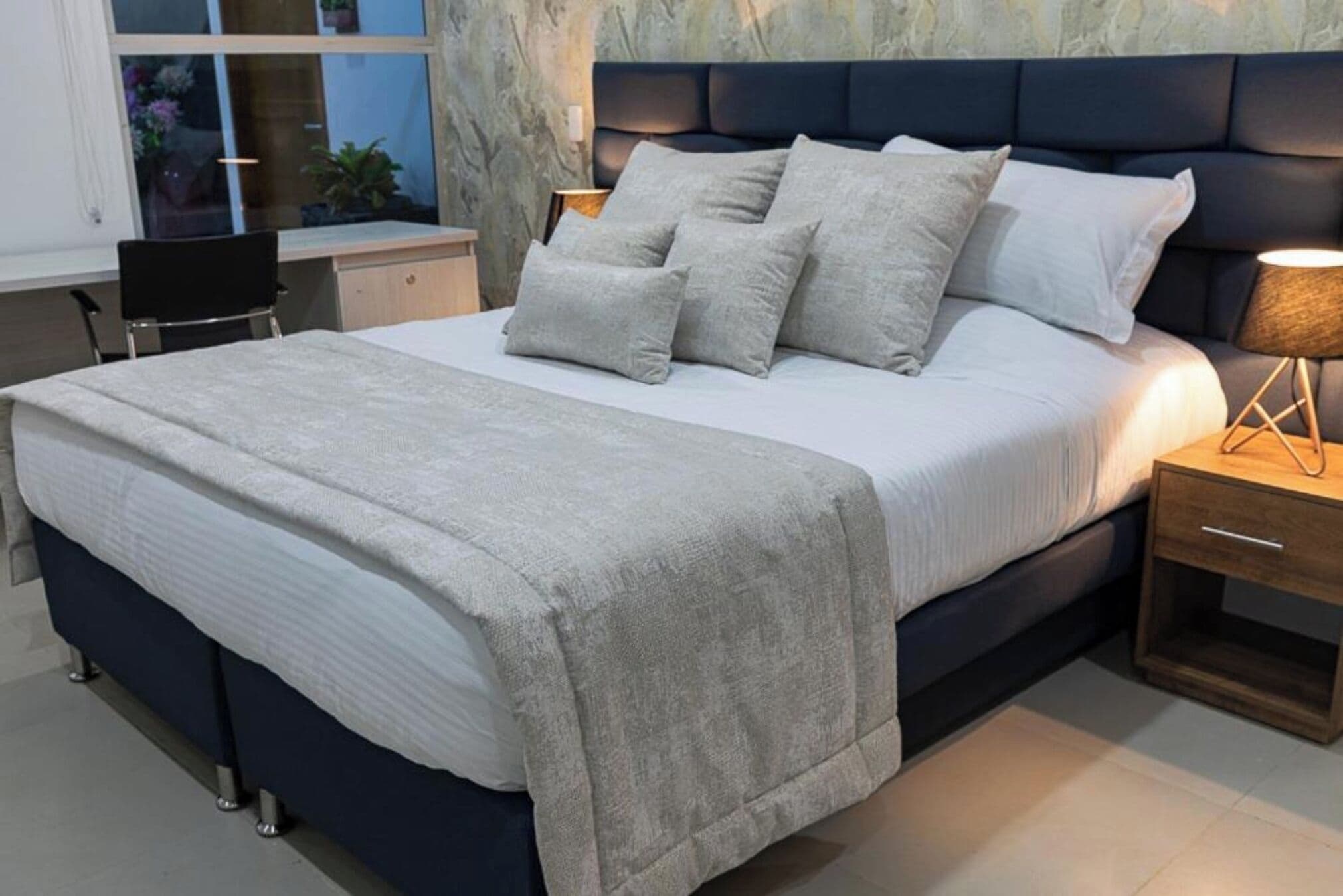 A modern bedroom with a large bed, a desk, and a chair.