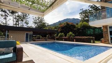 Una piscina al aire libre, sombrillas, sillones reclinables de piscina