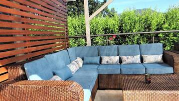 A sectional sofa with multiple cushions, a wicker coffee table, and a wooden slatted wall.