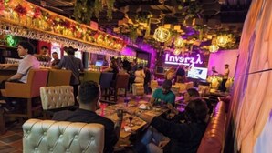 A restaurant with multiple dining tables and booths, a stage with a performer, and a neon sign in the background. -  Libertg Hotels Spa Medellin (Copacabana)