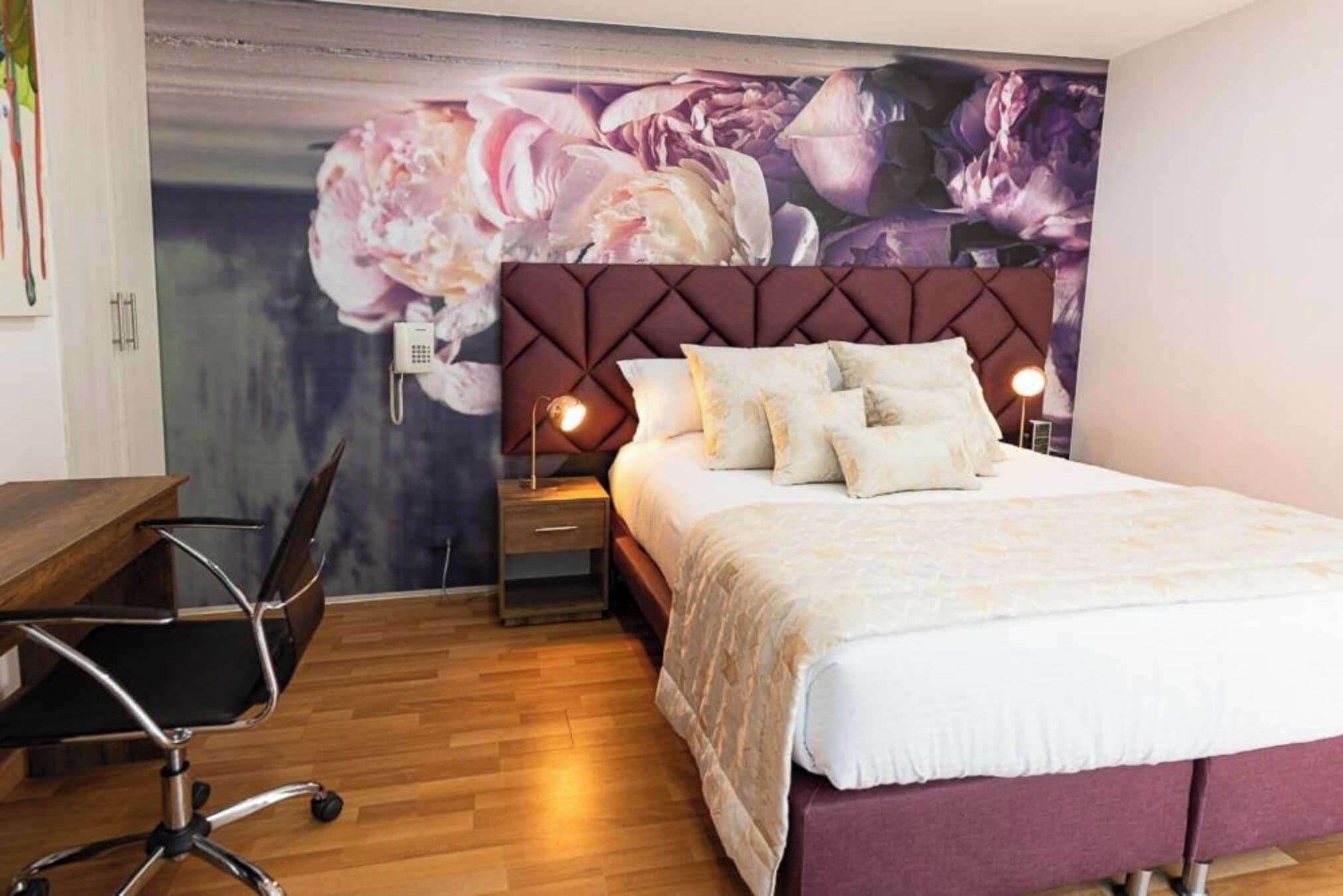 A bedroom with a large bed, a desk, and a chair.