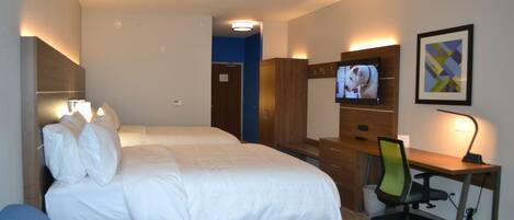 A hotel room with a bed, a desk, a chair, a TV, and a framed picture on the wall.