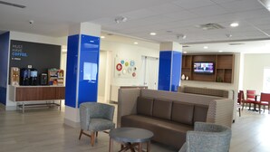 A modern lobby with a coffee station, seating area, and a television. - Holiday Inn Express Tallahassee University Central by IHG (Tallahassee)