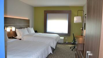 A hotel room with two beds, a desk, a chair, a lamp, and a window.