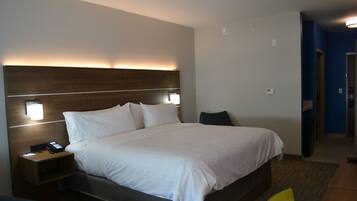 A hotel room with a large bed, bedside tables, a nightstand, and a wall-mounted lamp.