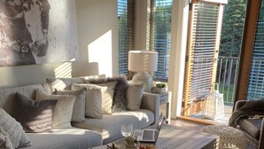 Ein modernes Wohnzimmer mit einer Couch, einem Couchtisch und Blick auf einen Balkon.