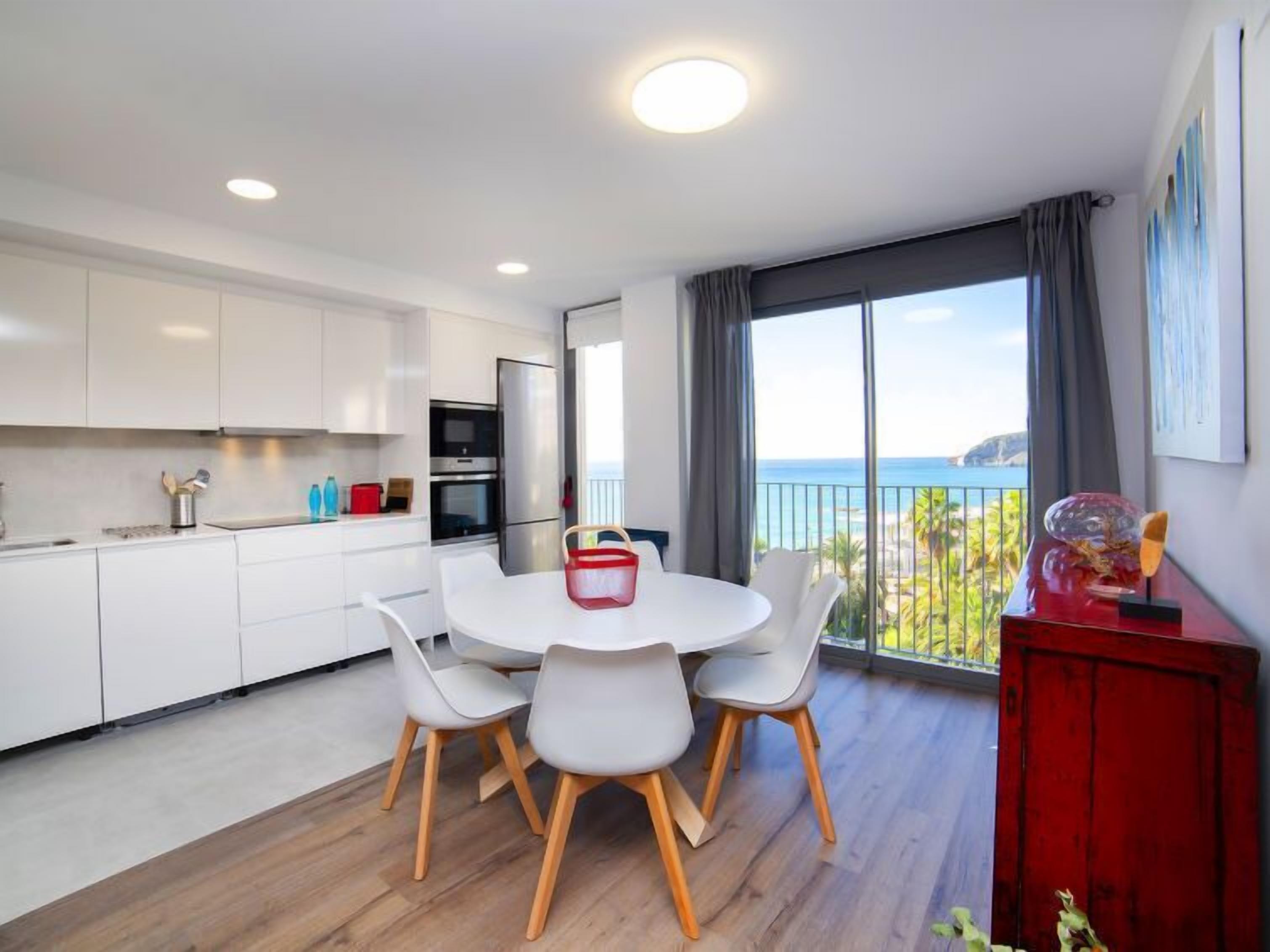 A modern kitchen with white cabinets and a dining area with a round table and chairs.