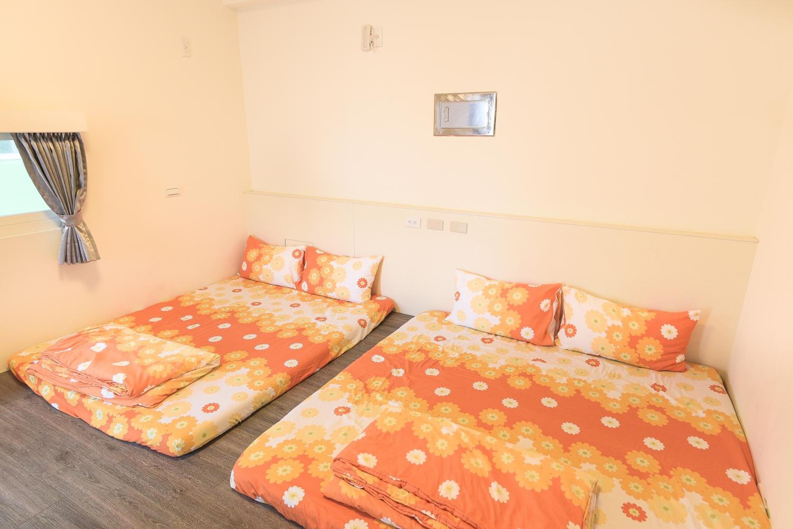 Habitación de hotel con dos camas individuales, cada una con ropa de cama y almohadas estampadas con motivos florales.