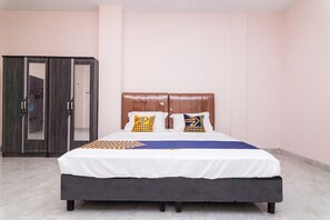 A bedroom with a bed, two pillows, a wardrobe, and a tiled floor. - OYO 1917 Mamora Homestay (Batam)