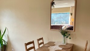 Ein Essbereich mit einem Holztisch, vier Stühlen, einem Spiegel und einer Vase mit Blumen.