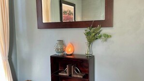 Ein Zimmer mit einer dunklen Holzkonsole, einem Spiegel, einer Vase mit Grünpflanzen und einer kleinen Holzkiste mit dem Aufdruck 'SUPPLY'.