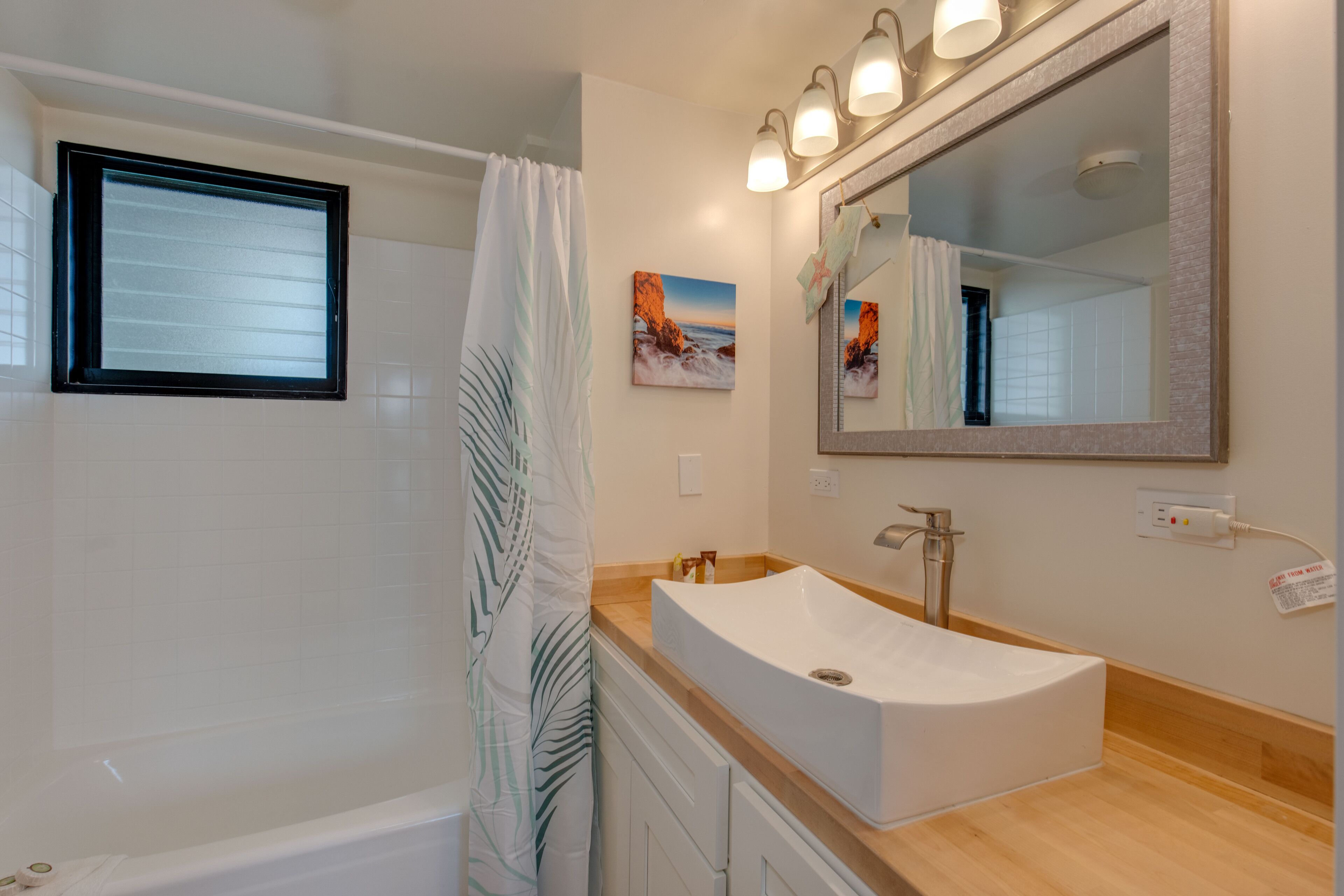 A bathroom with a bathtub, a sink with a large mirror, and a shower curtain.