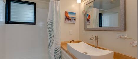 A bathroom with a bathtub, a sink with a large mirror, and a shower curtain.