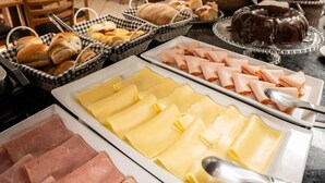 Un bufé con una variedad de alimentos, entre ellos carnes, quesos y pasteles.