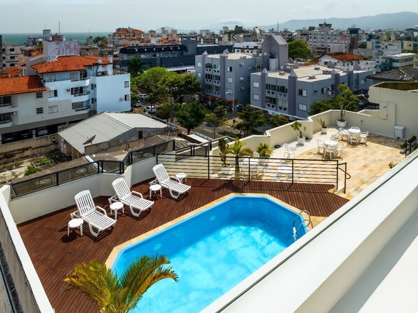 Una piscina al aire libre, sombrillas, sillones reclinables de piscina