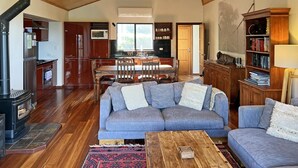 A spacious living room with a large gray sectional sofa, a wooden coffee table, and a fireplace. - Serendeva: Private, panoramic views, dogs allowed & EV charger (Shadforth)
