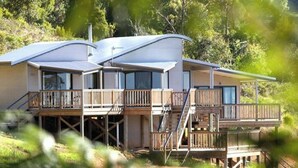 A modern two-story house with a flat roof, wooden deck, and large windows. - Serendeva: Private, panoramic views, dogs allowed & EV charger (Shadforth)