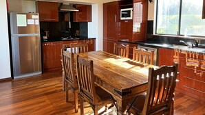 A modern kitchen with wooden cabinets, a stainless steel refrigerator, and a wooden dining table with chairs. - Serendeva: Private, panoramic views, dogs allowed & EV charger (Shadforth)