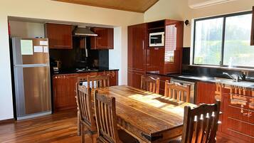 A modern kitchen with wooden cabinets, a stainless steel refrigerator, and a wooden dining table with chairs.