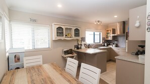 Una cocina moderna con una isla central, armarios blancos y un comedor con mesa y sillas de madera.