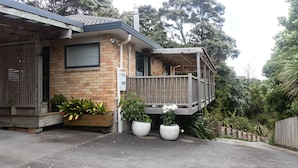 Una casa de dos pisos con terraza de madera y plantas en macetas.