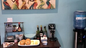 Una encimera de cocina con cafetera, dispensador de agua y diversos alimentos.