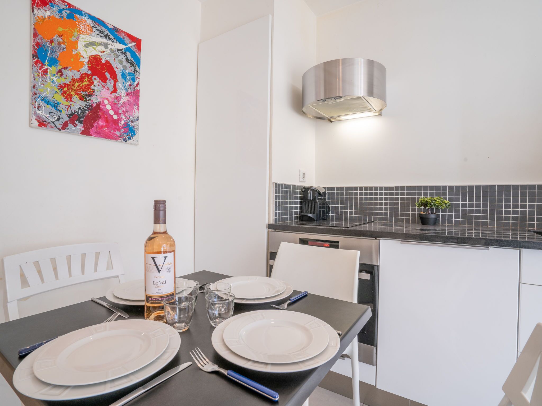 A modern kitchen with a black countertop, stainless steel appliances, and a decorative backsplash.