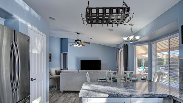 A modern kitchen with a large island, stainless steel appliances, and a ceiling fan. - Desert Oasis - Heated Pool, Putting Green, Lots of Parking (Gilbert)