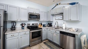 A modern kitchen with stainless steel appliances, light blue cabinets, and a granite countertop.