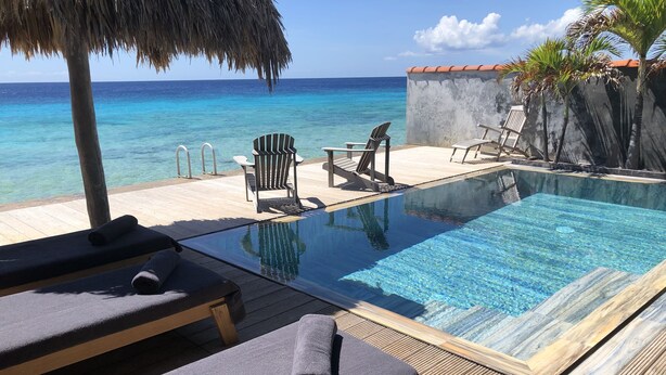 Ein Poolbereich mit Liegestühlen, einem kleinen Pool und Blick auf den Ozean.