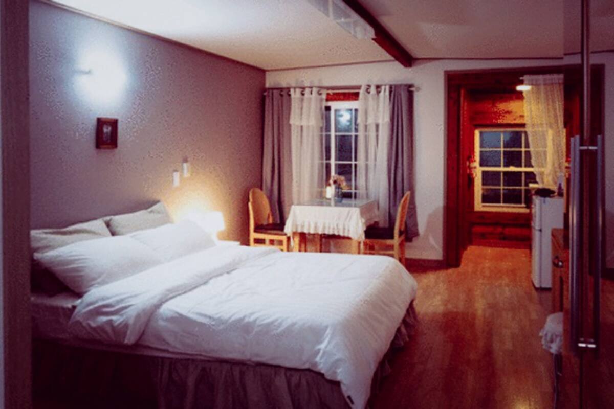 A bedroom with a bed, a small table, and chairs.