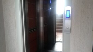 Ein Aufzug mit digitaler Anzeige und einer Tür zu einer Treppe.