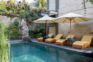 Una piscina al aire libre, sombrillas, sillones reclinables de piscina