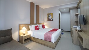 A hotel room with a bed, bedside tables, a TV, and a desk. - Capital O 2166 Elitya Stay (Denpasar)