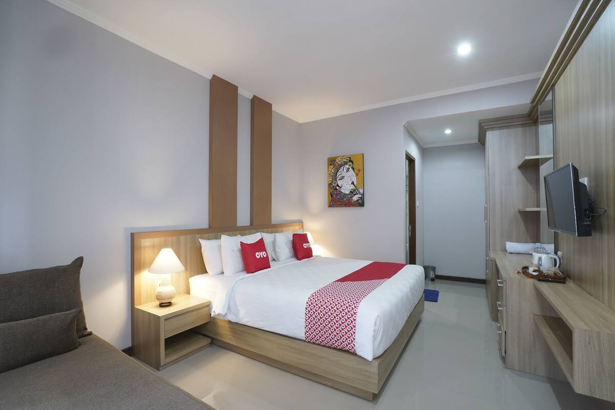 Une chambre d’hôtel équipée d’un lit, de tables de chevet, d’une télévision et d’un bureau.