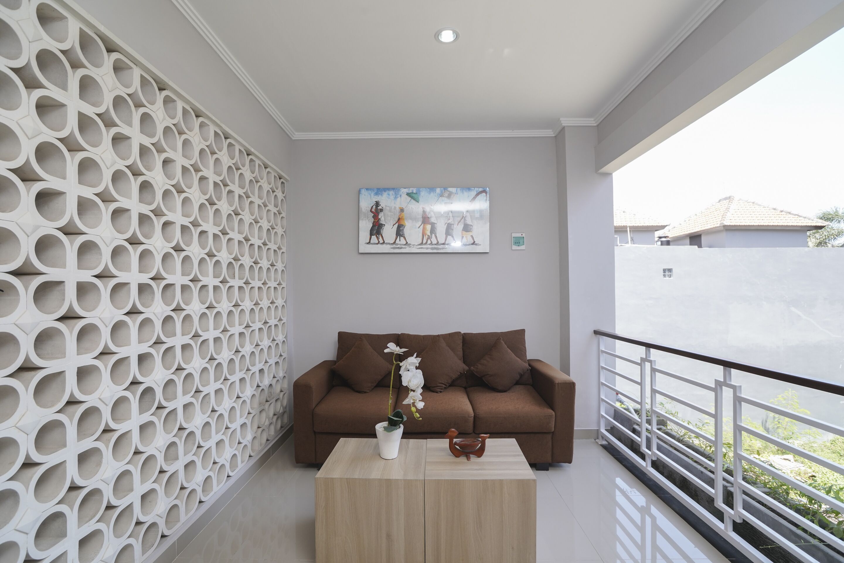 Una sala moderna con pared estampada, un sofá marrón, una mesa de centro con un jarrón y una escultura de pájaro, y un cuadro sobre el sofá.