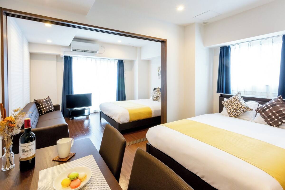 A hotel room with two beds, a TV, a dining area with a table and chairs, and a large mirror.