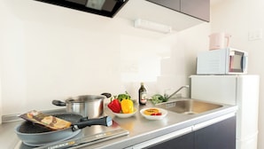 Une cuisine moderne équipée d’une cuisinière en acier inoxydable, d’un four à micro-ondes, d’un évier et d’une variété de légumes frais.