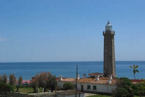 A coastal view with a prominent lighthouse and a building with a tiled roof. - In a front line beach, direct acess beach (Estepona)