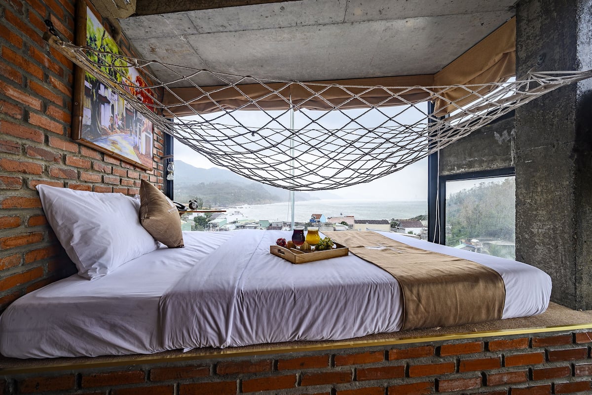 A bed with a view of the sea, a hammock, and a tray of fruit.