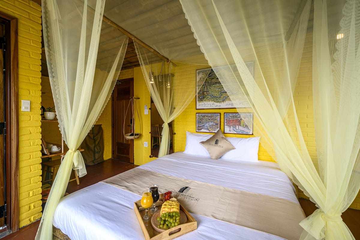 A bed with a canopy, a tray with fruits and drinks, and a map on the wall.